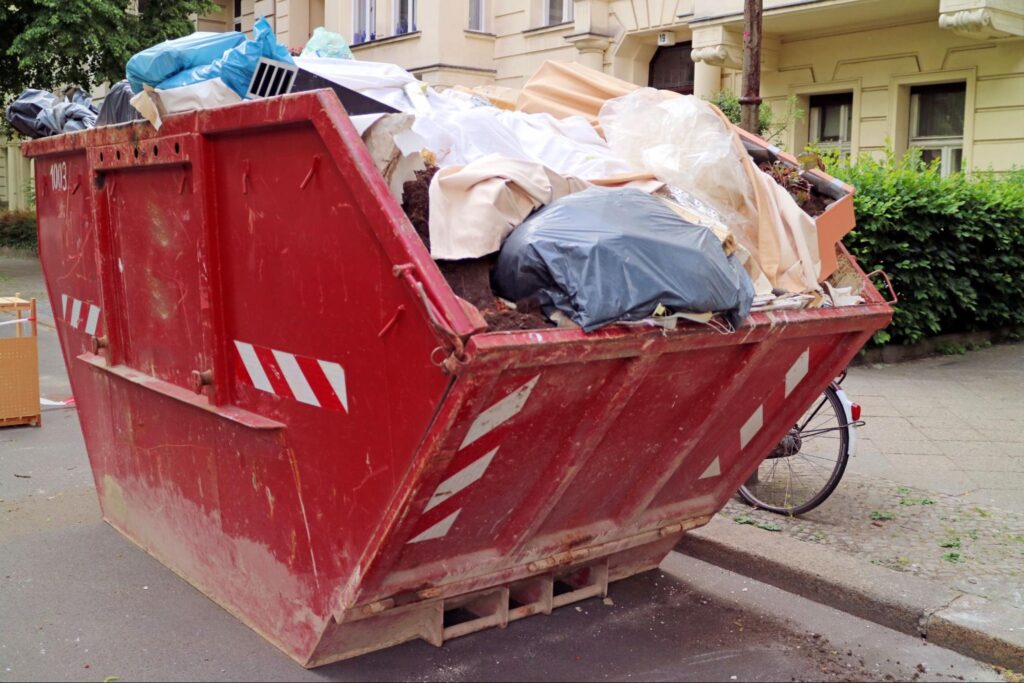 Offener Entrümpelungscontainer vor einem Wohngebäude im Einsatz