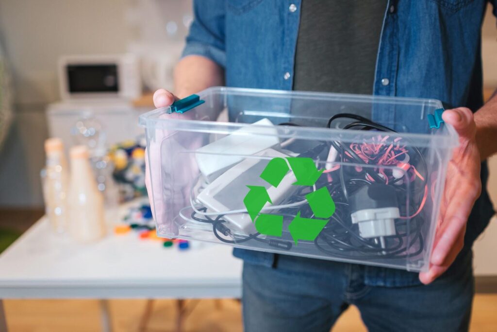 Sortierter Elektroschrott mit Laptop, Wasserkocher und Kabeln vor der Abholung durch ein Entrümpelungsteam